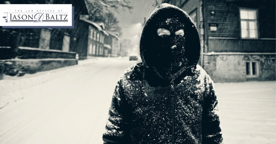 Person wearing a facemask with snow on their jacket and snow on the ground